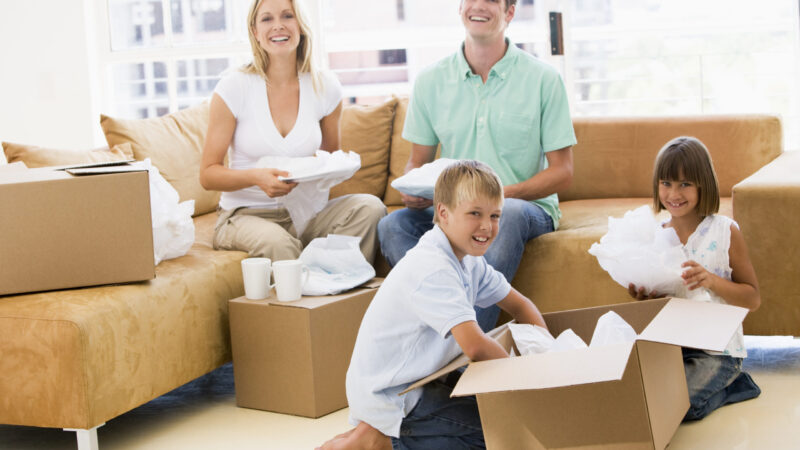 Family unpacking boxes in new home smiling
